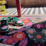 Droogloopmat en deurmat van Studio LilaLine met een speelse bloemvorm in tinten roze, oranje en groen – het ontwerp doet denken aan een vrolijk uitgestoken koekje met een knipoog naar retro bloemmotieven. De mat is slijtvast, neemt goed vocht op en zorgt voor een kleurrijke en uitnodigende entree, zowel praktisch als decoratief.