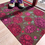 Droogloopmat met roze dahlia's op een zachte mosgroene achtergrond. Een frisse, elegante lenteprint die rust en vrolijkheid combineert.
