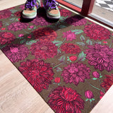 Droogloopmat met roze dahlia's op een zachte mosgroene achtergrond. Een frisse, elegante lenteprint die rust en vrolijkheid combineert.
