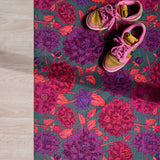 Droogloopmat met grote dahlia's in paars, roze en rood op een diepe petrolkleur. Een uitbundige bloemenprint vol zomerse energie.