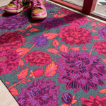Droogloopmat met grote dahlia's in paars, roze en rood op een diepe petrolkleur. Een uitbundige bloemenprint vol zomerse energie.