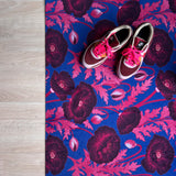 Droogloopmat met roze klaprozen die oplichten tegen een felblauwe achtergrond. Een verrassende winterprint vol kleur en optimisme.
