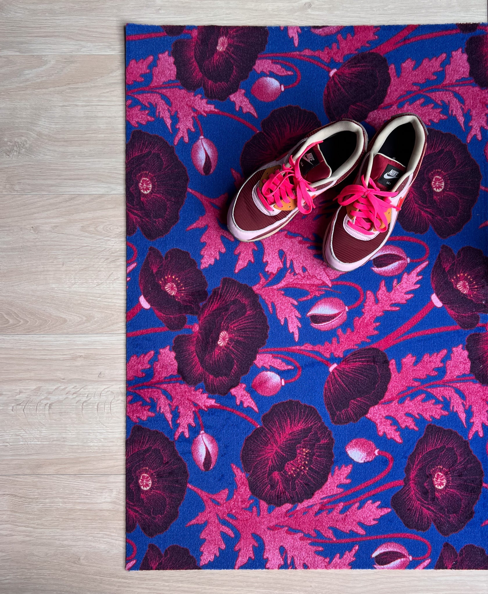 Droogloopmat met roze klaprozen die oplichten tegen een felblauwe achtergrond. Een verrassende winterprint vol kleur en optimisme.