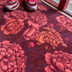 Droogloopmat met warme pioenrozen in koraal en oranje op een bordeauxrode ondergrond. Ideaal voor een gezellige en knusse herfstsfeer in huis.