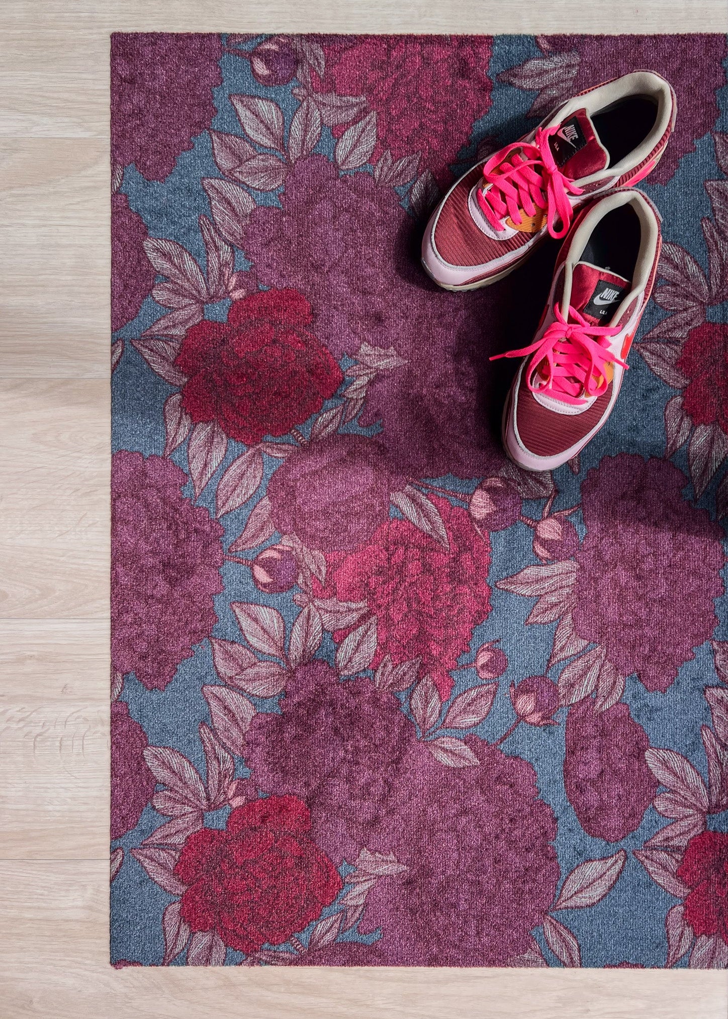 Droogloopmat met oudroze en rode pioenrozen op een vergrijsd blauwe ondergrond. Een elegante, winterse bloemenprint die rust en stijl brengt.