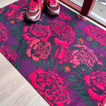 Droogloopmat met uitbundige felroze pioenrozen op een diepe paarse achtergrond. Een vrolijke, zomerse bloemenmat vol energie en kleur.