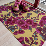 Droogloopmat met roze stokrozen op een warme okergele achtergrond. Een vrolijke lentemix die meteen zon en bloemen de hal binnenbrengt.