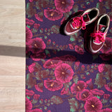 Droogloopmat met roze stokrozen op een diepe paarse ondergrond. Een rijke, zomerse print vol charme en contrast.