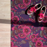 Droogloopmat met roze stokrozen op een diepe paarse ondergrond. Een rijke, zomerse print vol charme en contrast.