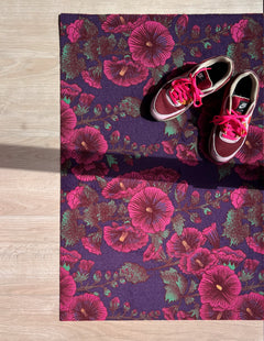 Droogloopmat met roze stokrozen op een diepe paarse ondergrond. Een rijke, zomerse print vol charme en contrast.