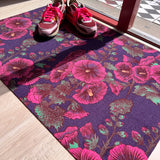 Droogloopmat met roze stokrozen op een diepe paarse ondergrond. Een rijke, zomerse print vol charme en contrast.