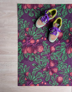 Droogloopmat met vijgenbladmotief in mauve met accenten van donkerpaars en donkergroen. Een diepe, zomerse print met mediterrane warmte.