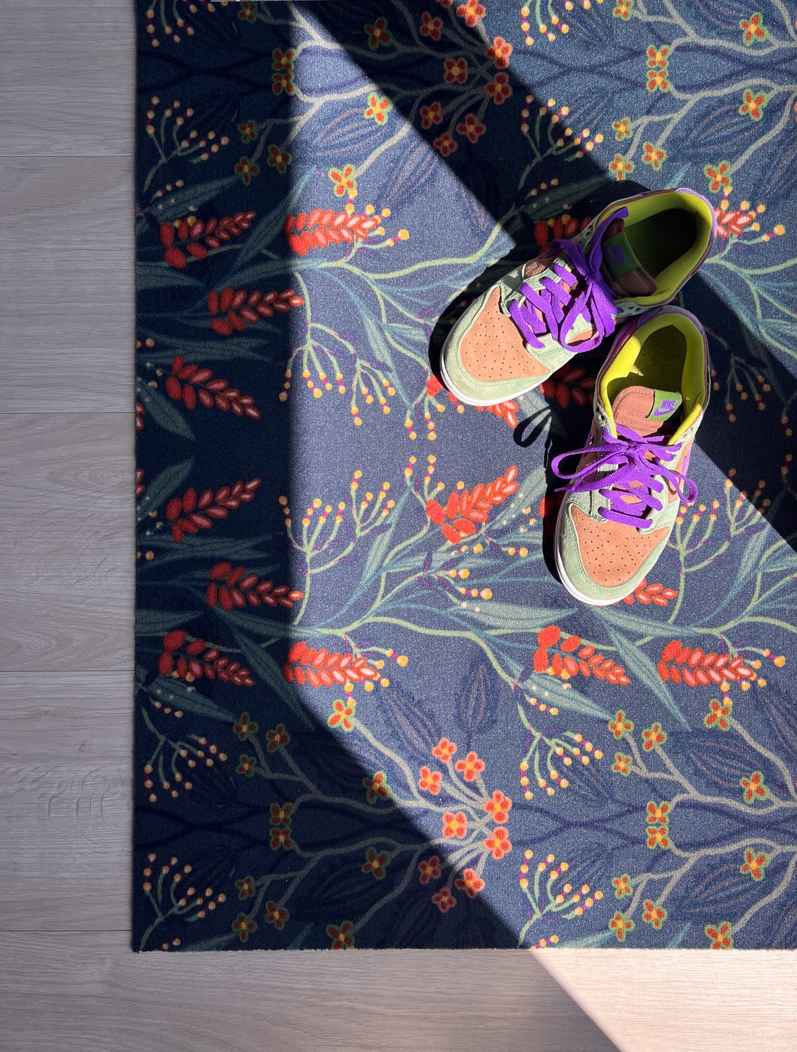 Op maat gemaakte droogloopmat van Studio LilaLine met een sierlijk patroon geïnspireerd op bloeiende blauwe regen – uitgevoerd in diepe petroltinten met verfijnde bloemvormen die als een waterval over de mat lijken te hangen. De print heeft een rustige, elegante uitstraling. De mat is slijtvast, vochtopnemend en perfect voor een stijlvolle entree.