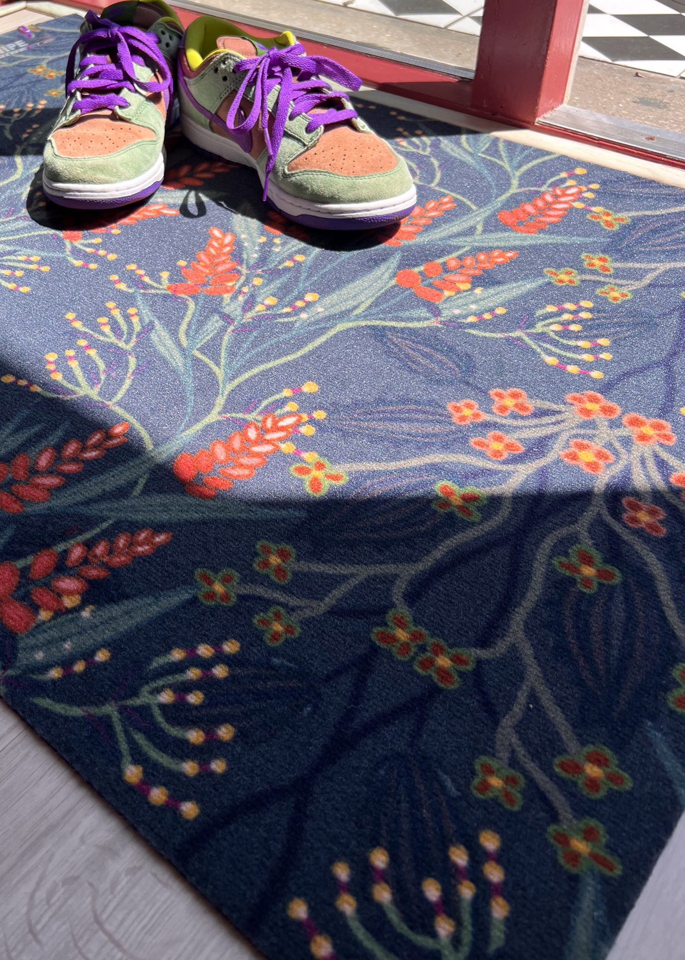 Op maat gemaakte droogloopmat van Studio LilaLine met een sierlijk patroon geïnspireerd op bloeiende blauwe regen – uitgevoerd in diepe petroltinten met verfijnde bloemvormen die als een waterval over de mat lijken te hangen. De print heeft een rustige, elegante uitstraling. De mat is slijtvast, vochtopnemend en perfect voor een stijlvolle entree.