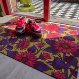 Droogloopmat met felroze zonnebloemen op een mosterdgroene achtergrond. De vrolijke bloemenprint geeft een frisse lentesfeer en maakt de entree warm en uitnodigend.