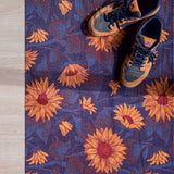 Droogloopmat met okergele zonnebloemen op een diepe donkerblauwe ondergrond. Een krachtige, winterse bloemenprint die sfeer en warmte brengt bij binnenkomst.