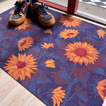 Droogloopmat met okergele zonnebloemen op een diepe donkerblauwe ondergrond. Een krachtige, winterse bloemenprint die sfeer en warmte brengt bij binnenkomst.