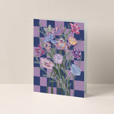 Dubbelgevouwen A6-kaart van Studio LilaLine met op de voorkant een speels ontwerp – een blauw-roze geblokt patroon als achtergrond met in het midden een pastel boeket bloemen. De bloemen zijn zacht en dromerig, met tinten die mooi afsteken tegen het grafische dambord. Het contrast tussen het patroon en het boeket geeft de kaart een frisse, vrolijke uitstraling. De binnenkant is blanco en biedt ruimte voor een persoonlijke boodschap.
