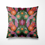 Kussen voor binnen en buiten met een speels bloemenpatroon in warme tinten als oranje, aubergine, zachtgroen en paars. De bloemen hebben iets weg van vrolijke koekjes met glazuur, wat het ontwerp een luchtige en vrolijke uitstraling geeft. De achtergrond is donkergroen en zorgt voor een mooi contrast. Gemaakt van stevige, waterafstotende stof, perfect voor zowel binnen op de bank als buiten in de tuin of op het balkon.