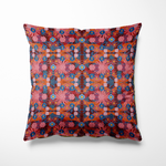 Kussen voor binnen en buiten met een kleurrijke bloemenprint in warme tinten rood, roze en oranje, aangevuld met accenten van kobaltblauw en zonnig geel. De print is rijk en gedetailleerd, als een liefdesexplosie in bloei. Het patroon is symmetrisch opgebouwd en voelt feestelijk, speels en toch gebalanceerd. Gemaakt van stevige stof die geschikt is voor zowel binnen op de bank als buiten op je loungeset.