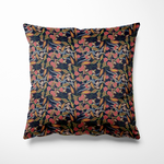 Vierkant kussen geschikt voor binnen en buiten, met een gedetailleerde botanische print op een diepe, donkerblauwe achtergrond. De illustratie toont sierlijke bladeren in grijs, oranje en roestrood, afgewisseld met roze bloemen en groene bessen. De print heeft een verfijnde urban jungle vibe met een vleugje vintage flair – perfect voor wie houdt van karakter en kleur in huis of tuin.