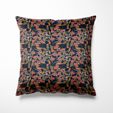 Vierkant kussen geschikt voor binnen en buiten, met een gedetailleerde botanische print op een diepe, donkerblauwe achtergrond. De illustratie toont sierlijke bladeren in grijs, oranje en roestrood, afgewisseld met roze bloemen en groene bessen. De print heeft een verfijnde urban jungle vibe met een vleugje vintage flair – perfect voor wie houdt van karakter en kleur in huis of tuin.
