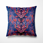 Vierkant binnen- en buitenkussen met een verfijnde symmetrische bloemenprint in rood, roze, lila en paars, met sierlijke takken en blaadjes die lijken te dansen over een diepe kobaltblauwe achtergrond. De print bevat ook kleine gele stipjes als accent. Een elegante eyecatcher die kleur en karakter toevoegt aan je tuinbank of woonkamer.