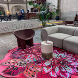 Luxe vloerkleed Dahlia Roze van Studio LilaLine met drie grote dahlia-bloemen in de hoofdrol – de bloemen zijn weelderig en gelaagd, opgebouwd uit rijke roze en rode tinten met hier en daar een warme oranje gloed. De vormen zijn rond en zacht, alsof de bloemblaadjes zich langzaam ontvouwen. Het kleed voelt zacht en warm aan, en straalt een romantische, uitnodigende sfeer uit in de ruimte.