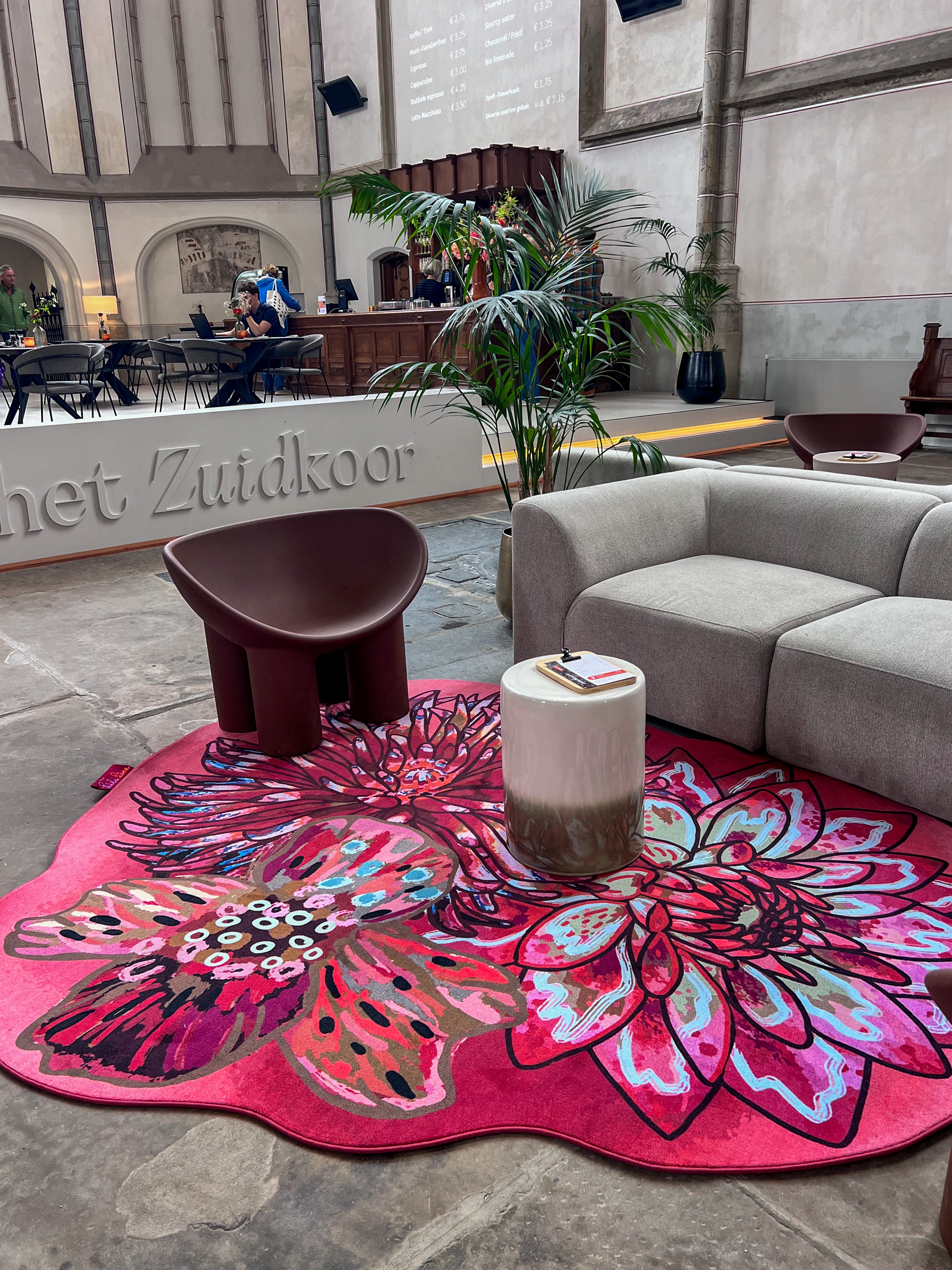 Luxe vloerkleed Dahlia Roze van Studio LilaLine met drie grote dahlia-bloemen in de hoofdrol – de bloemen zijn weelderig en gelaagd, opgebouwd uit rijke roze en rode tinten met hier en daar een warme oranje gloed. De vormen zijn rond en zacht, alsof de bloemblaadjes zich langzaam ontvouwen. Het kleed voelt zacht en warm aan, en straalt een romantische, uitnodigende sfeer uit in de ruimte.