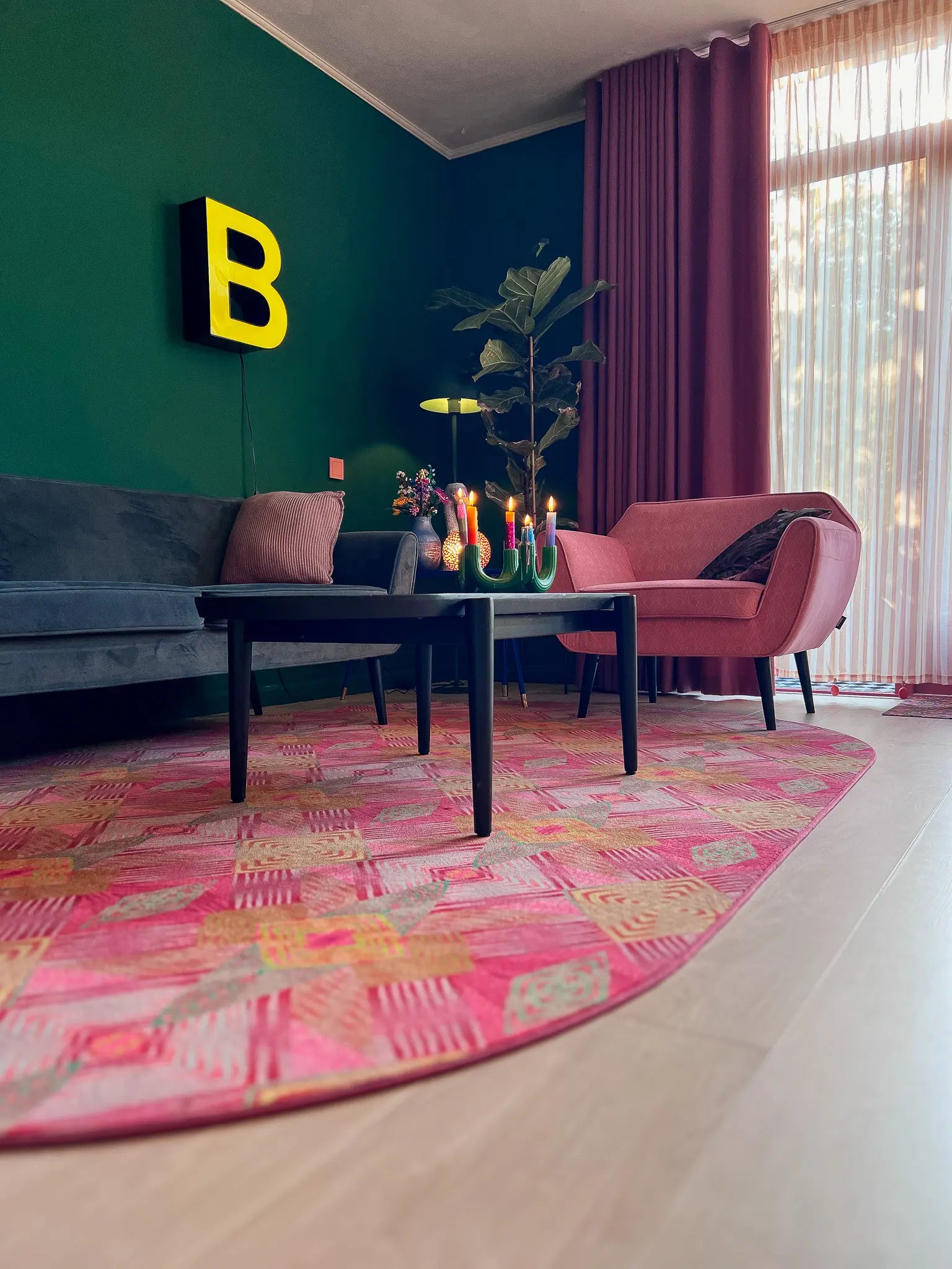 Luxe vloerkleed Diamond Pink van Studio LilaLine met een grafisch diamantpatroon in roze, groen en subtiele goudtinten – het kleed voelt zacht maar stevig aan, en het patroon bestaat uit ritmische vormen die in lagen over elkaar lijken te schuiven, alsof je naar een fonkelende caleidoscoop kijkt. De kleuren zijn warm, levendig en geven het kleed een rijke en speelse uitstraling.