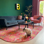 Luxe vloerkleed Diamond Pink van Studio LilaLine met een grafisch diamantpatroon in roze, groen en subtiele goudtinten – het kleed voelt zacht maar stevig aan, en het patroon bestaat uit ritmische vormen die in lagen over elkaar lijken te schuiven, alsof je naar een fonkelende caleidoscoop kijkt. De kleuren zijn warm, levendig en geven het kleed een rijke en speelse uitstraling.